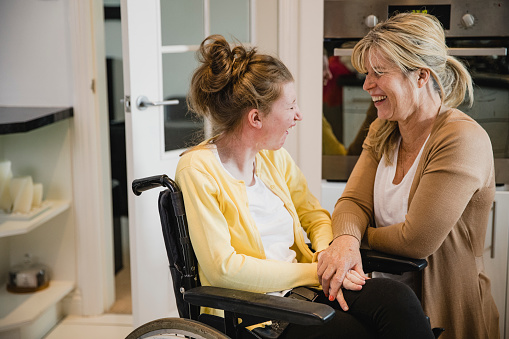 Jeune femme en situation de handicap dans un fauteuil roulant, accompagnée de sa maman
